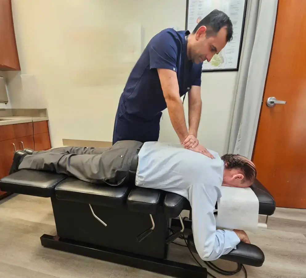 Chiropractor performing back adjustment on patient